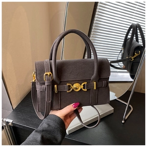 Detail view of a vintage dark brown shoulder bag featuring gold buckle and round hardware