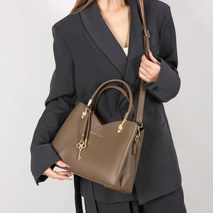 Close-up of dark brown lychee leather handbag with gold logo and key pendant accessory