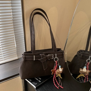 Close-up of a dark brown suede tote bag with belt buckle detail and cute bear charm