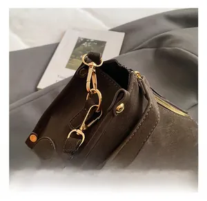 Close-up of golden metal hooks and shoulder strap connector on matte dark taupe handbag