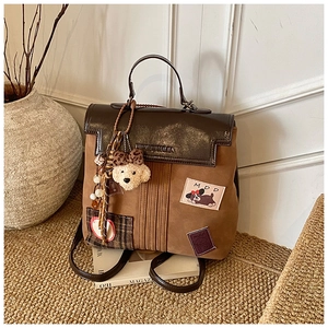 Detail of vintage brown backpack with cute plush bear charm and embroidered patch accents