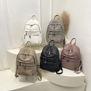 Detail of five PU leather backpacks in various colors with decorative zipper pulls