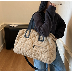 Close-up of quilted floral embroidery and zipper pocket on beige crossbody tote bag