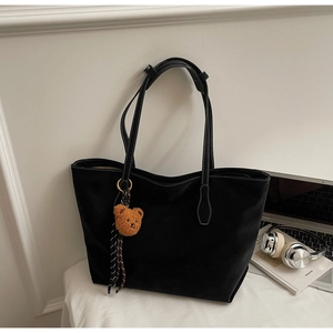 Détail d'un sac cabas noir mat avec coutures contrastées et charm d'ours marron
