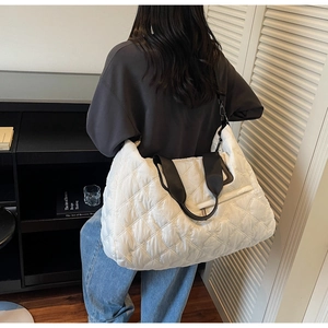 Detail view of white quilted gym bag with black shoulder strap and zipper pocket
