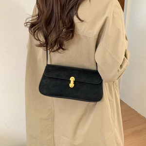 Detail of a black suede underarm bag with gold U-shaped buckle and fine strap