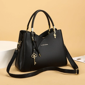 Detail of black lychee grain leather bucket bag with gold hardware and key charm pendant