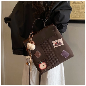 Détail du sac à dos vintage marron avec patchs brodés et pendentif en peluche douce