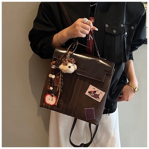 Vue détaillée du sac à dos marron foncé avec pendentifs mignons et écussons rétro