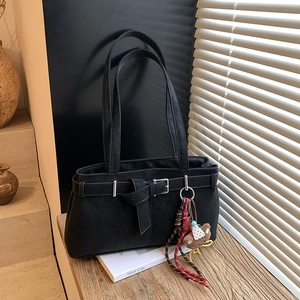 Detail of black matte shoulder bag featuring a metal buckle and a cute bear charm