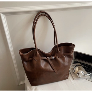 Detailed close-up of dark brown tote bag featuring matte leather texture and belt buckle decor