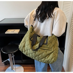 Detail view of large olive green quilted bag with padded texture and black straps