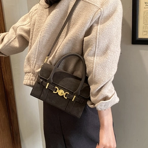 Detail of matte dark grey handbag with golden heart-shaped hardware lock and leather handle