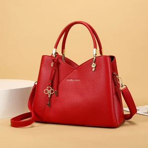 Detail of red lychee leather handbag with gold hardware and treble clef metal accents