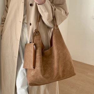 Détail du sac cabas minimaliste en cuir marron avec une pochette zippée assortie sur mannequin