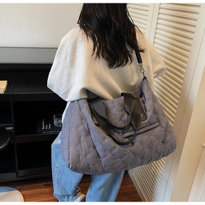 Detail of grey-purple quilted tote bag with embroidered bows and dual carrying straps