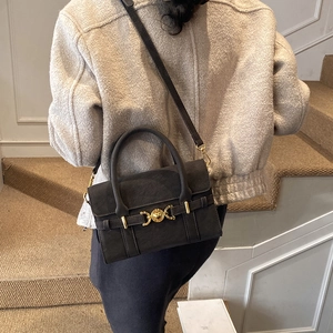 Detail of grey suede handbag featuring a vintage gold buckle and curved top handle