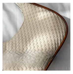 Macro shot of beige woven leather texture and silver zipper detail on the crossbody bag