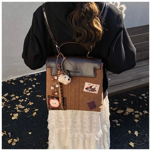 Detail of vintage brown backpack with cute dog patches and plush charm on autumn leaves