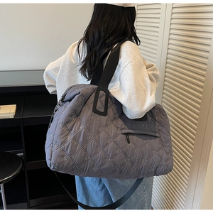 Detail view of dark grey quilted gym bag with intricate embroidery and wide shoulder strap