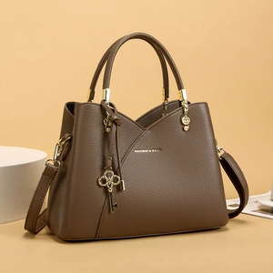 Detail of brown pebbled leather shoulder bag with gold hardware and key charms