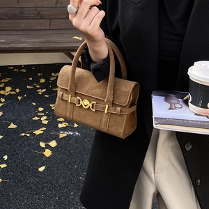 Detail of a brown matte leather tote bag featuring a gold ring lock and dual handles