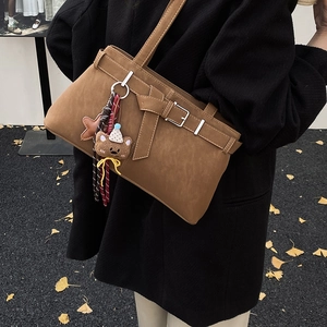 Brown suede shoulder bag with decorative belt buckle and cute bear charm detail