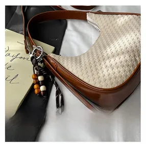 Detail of woven cream handbag with leather trim, wooden beads and silver zipper