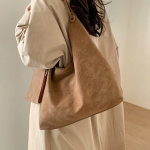 Détail du grand sac porté épaule en daim marron avec œillet métallique et pochette