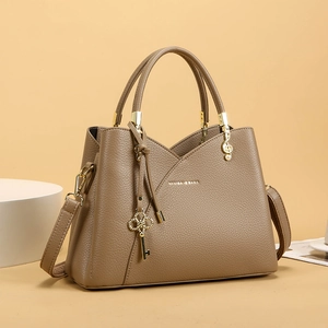 Close-up of brown lychee grain faux leather bucket bag with golden charms and hardware
