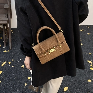 Detailed texture of brown matte suede shoulder bag with elegant gold metal bar closure