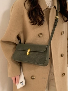 Minimalist olive green square underarm bag with gold buckle on a stylish coat