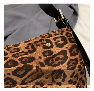 Detail of leopard print faux fur handbag featuring gold studs and black leather strap