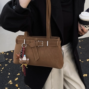 Detail of vintage brown shoulder bag with leather buckle and cute plush bear charm