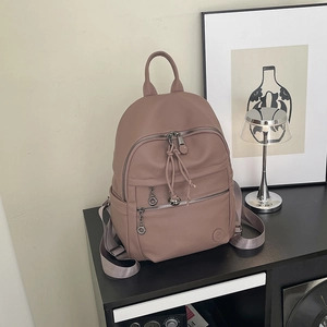 Detail of dusty pink pebbled leather backpack with sturdy grey woven straps and zippers