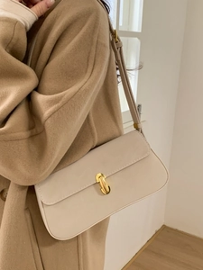 Minimalist beige underarm bag with gold clasp shown on a wool coat outfit