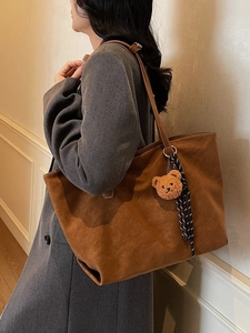 Grand sac cabas en daim caramel avec breloque ours et ruban, porté par un mannequin