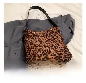 Macro detail of leopard print canvas tote bag featuring premium leather shoulder strap
