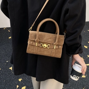 Detail of retro brown crossbody bag with gold buckle on autumn gingko leaf background