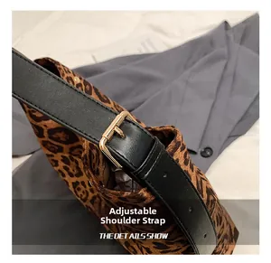 Detail of adjustable black leather shoulder strap with gold metal buckle on leopard bag