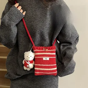 Detail of red and white striped knit phone bag with cute bear charm and wood button