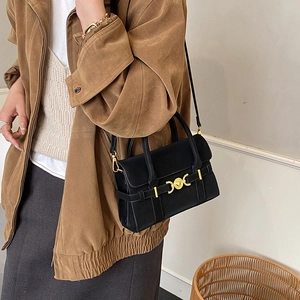 Detail view of a black faux leather crossbody bag with a gold heart clasp and top handle
