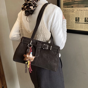 Detail of dark brown matte leather shoulder bag with buckle and cute bear charm
