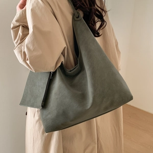 Détail d'un grand sac cabas vert foncé avec pochette assortie porté à l'épaule