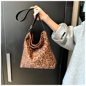 Detail of leopard print tote bag with adjustable black leather shoulder strap and gold buckle