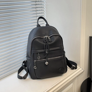 Detail of black lychee grain leather backpack with silver zippers and metal charms