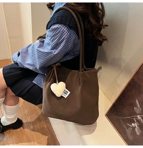 Detail of dark brown tote bag with fuzzy white heart pendant and Stay Story tag