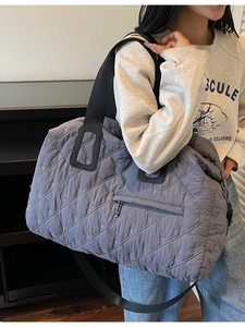 Grey quilted travel bag with bow embroidery and adjustable black shoulder strap