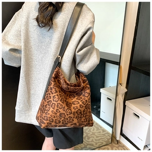 Rear view of a model wearing a leopard print tote bag with a wide black shoulder strap
