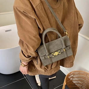 Detailed view of an olive green crossbody bag with gold hardware on a lifestyle model